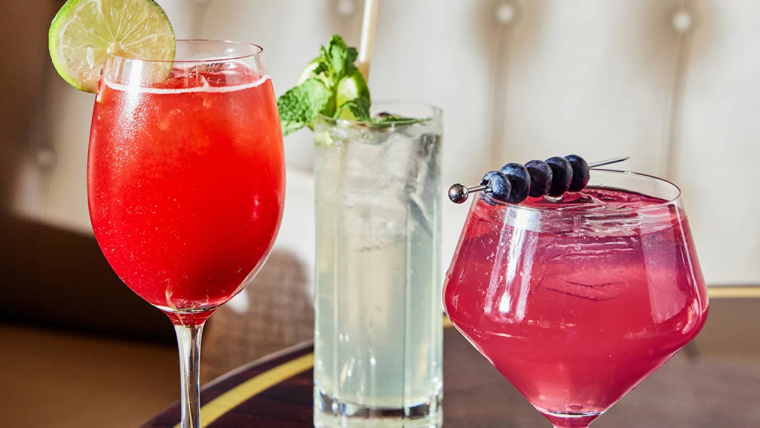 Three colourful cocktails on a black table with gold trim.