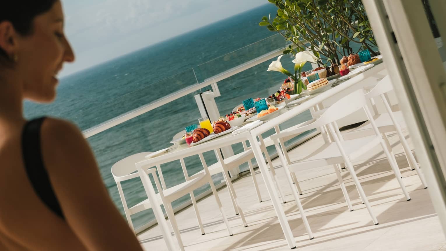 A parent and small child walk hand-in-hand toward a table with breakfast served on a private terrace