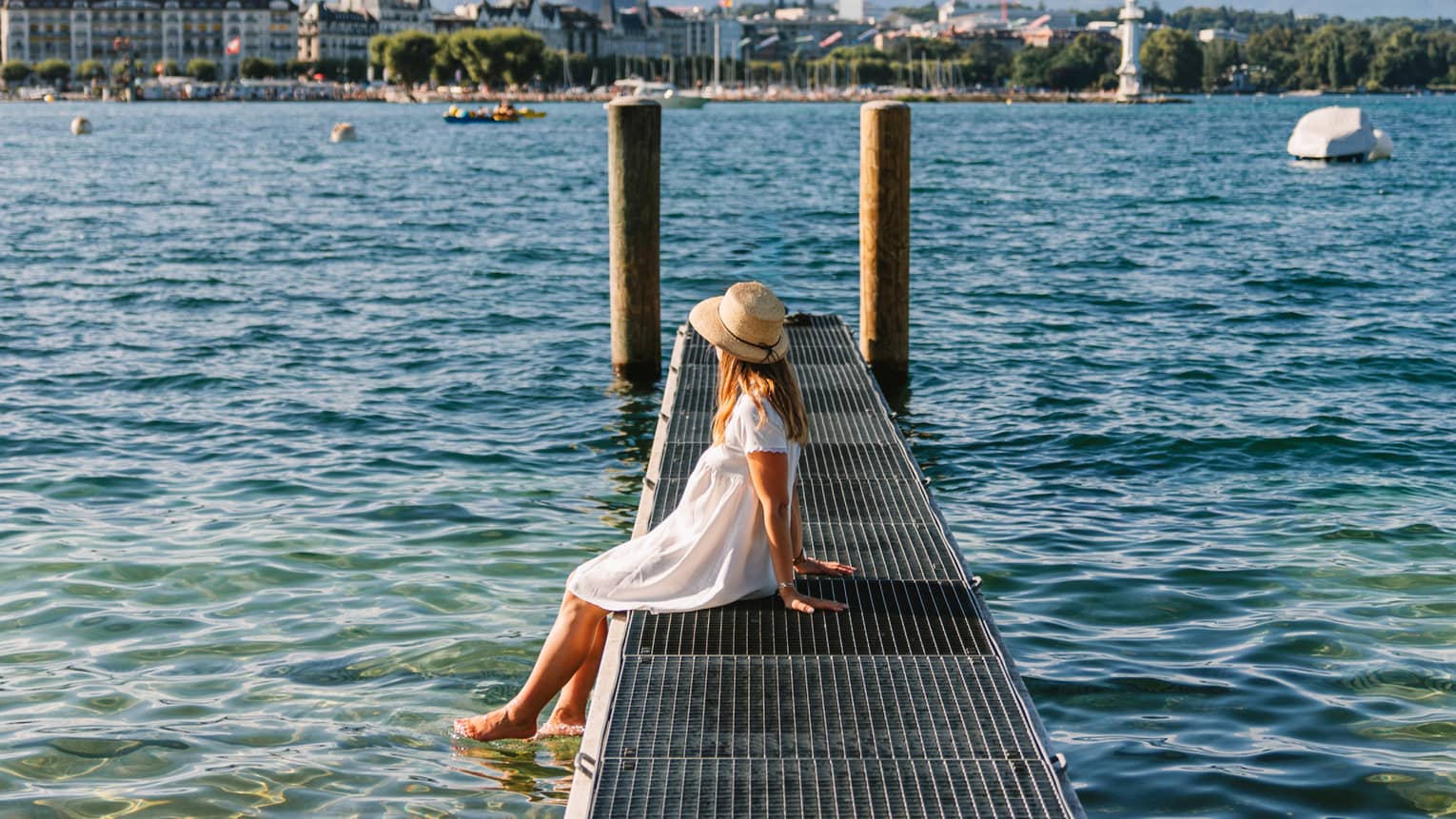Child sitting on a narrow metal dock leading to two pylons in calm lake