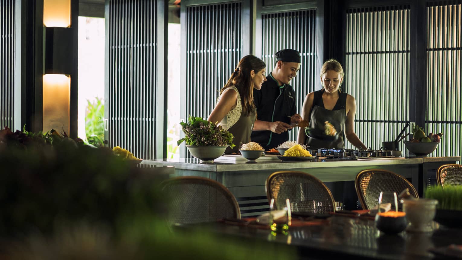 Chef, two women look at pan on kitchen range at Hoi An Cooking Academy 