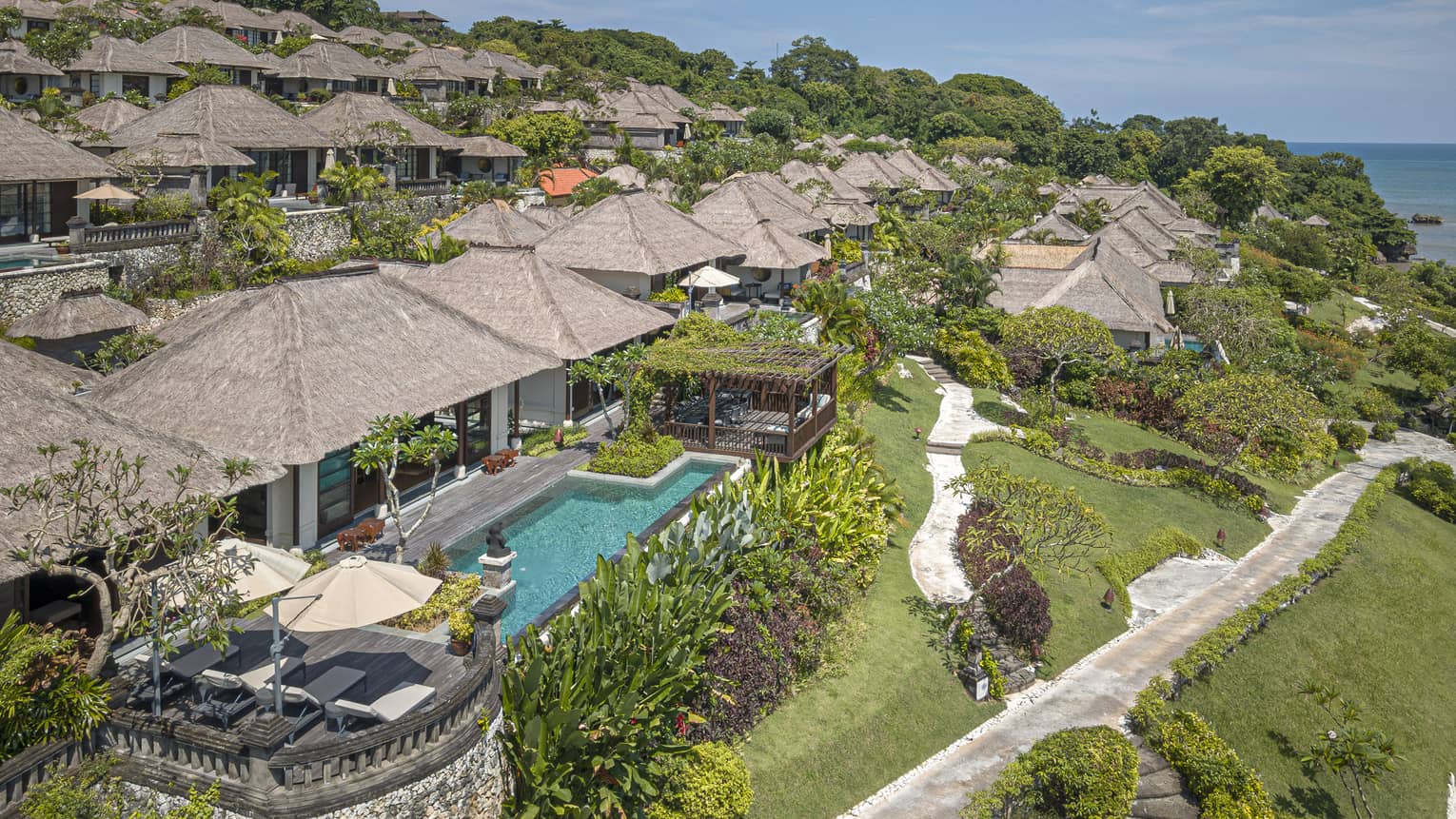 Aerial view of Royal Villa with pool, rolling green hills, ocean views