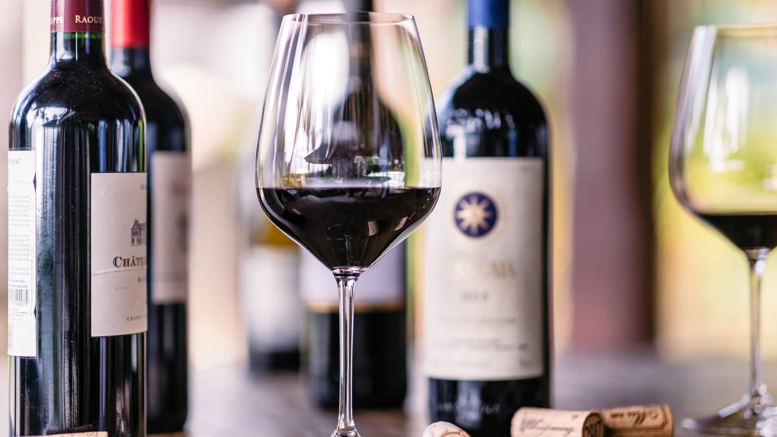 Closeup of glass of red wine, bottles beside it