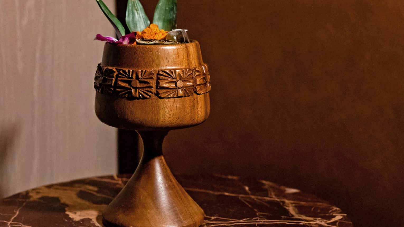 Crime of Passion signature drink available at Bandista, in carved wood vessel with pineapple stem garnish