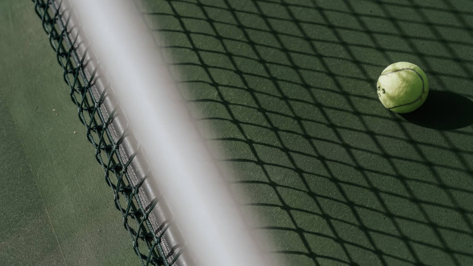 Tennis ball on tennis court with shadow of net