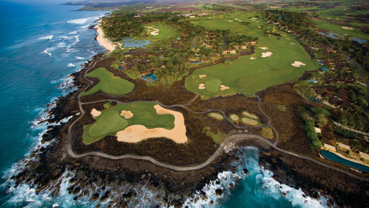 Aerial view of 18-hole golf course greens on volcanic rock by ocean