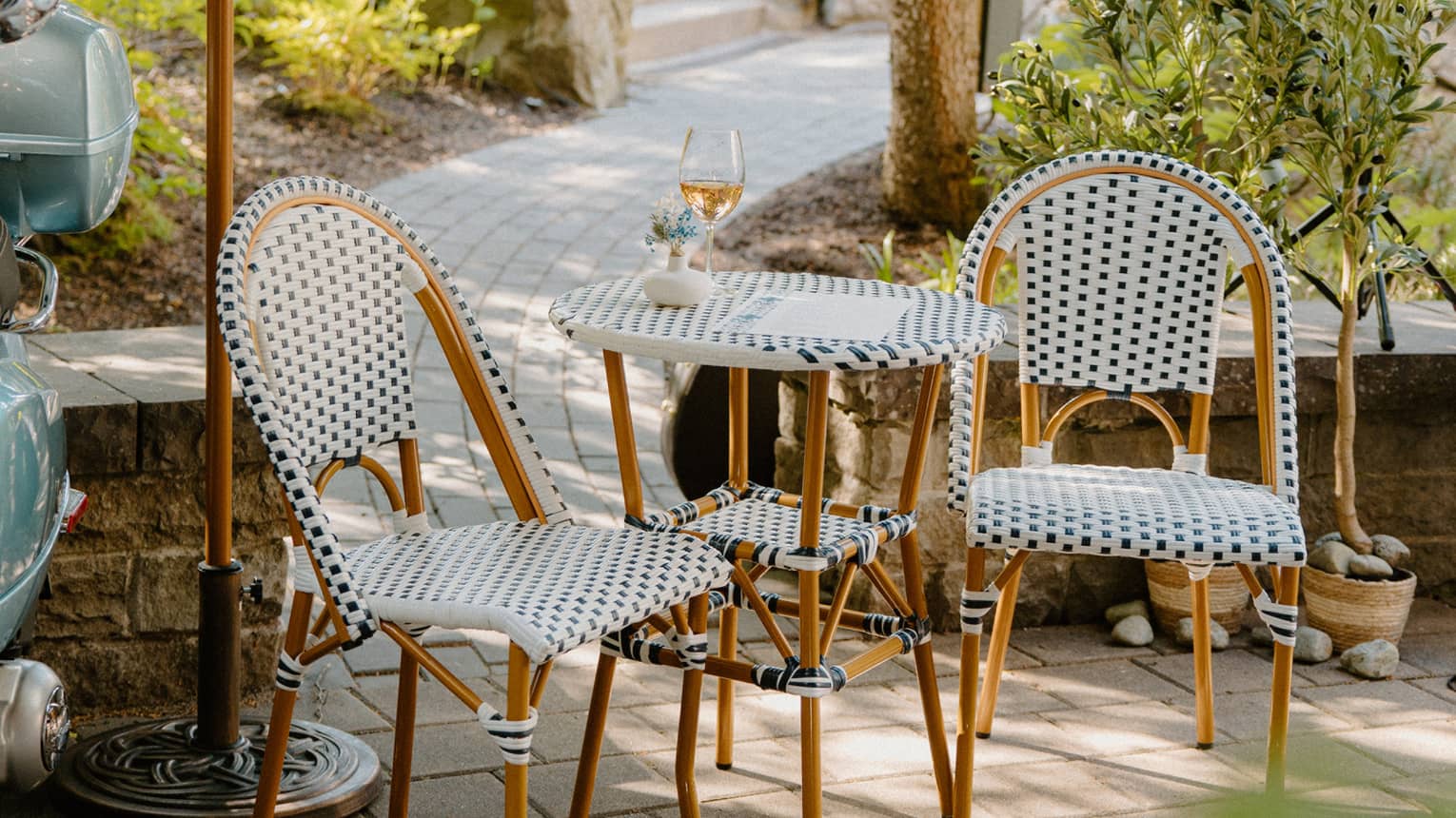 Two polka-dotted chairs and matching two-seater table on stone patio with walkway leading to steps