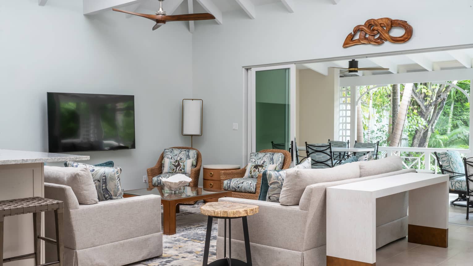Living room of private residence in tropical setting, with white, vaulted, wooden beam ceiling