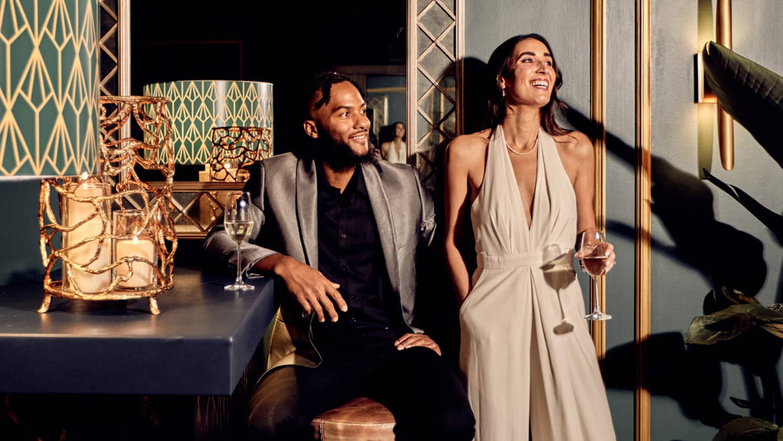 A man and woman leaning on a green wall with gold accents.
