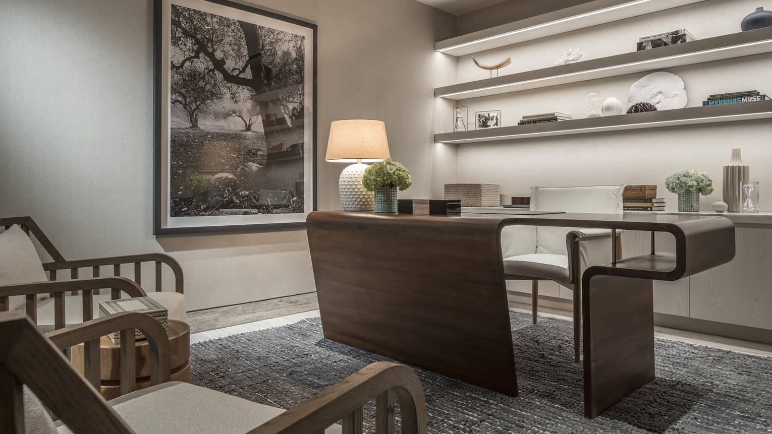 Arion Royal Suite office with built-in backlit shelves, large ergonomic wooden desk, grey area rug, twin armchairs