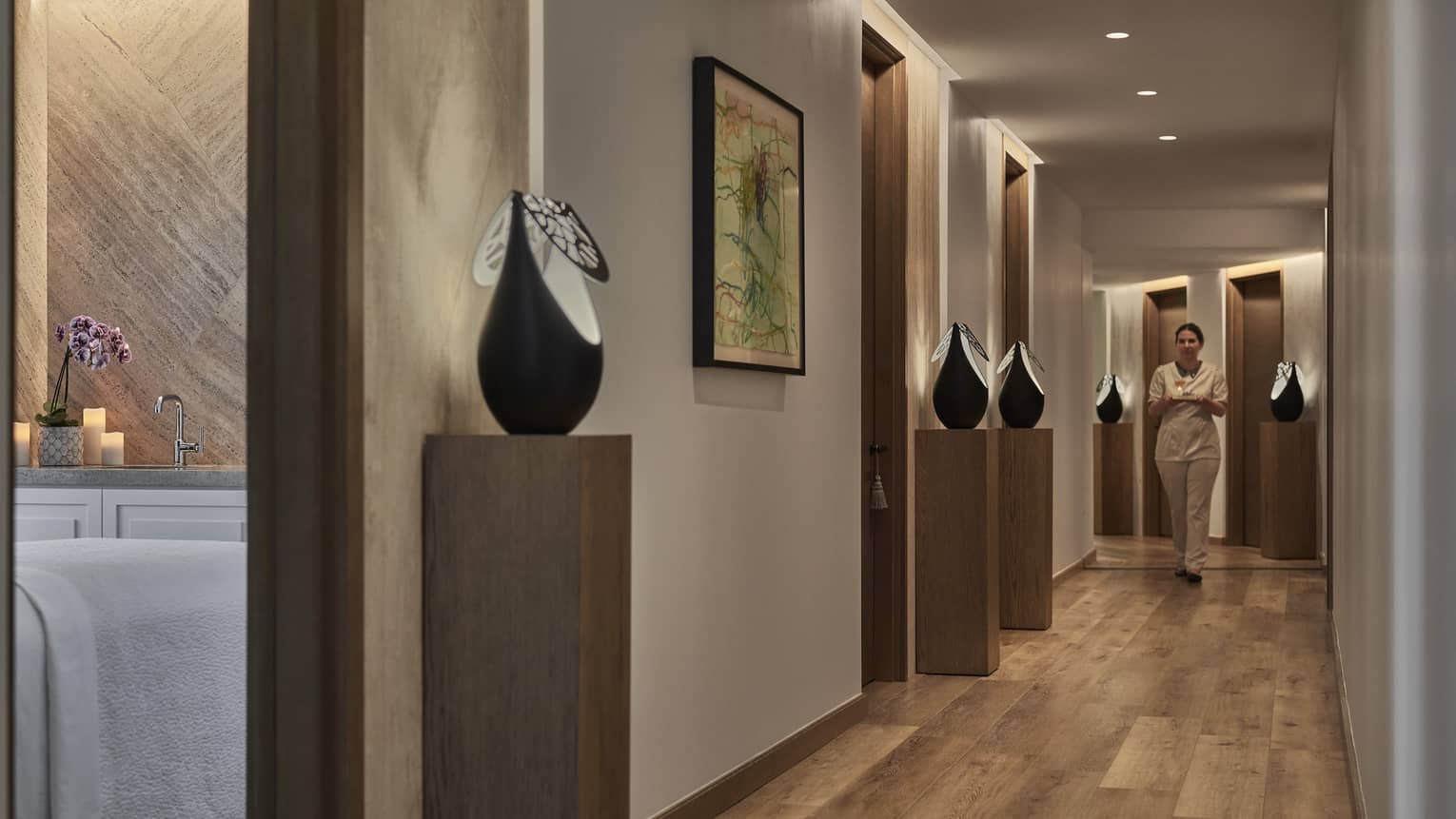 A spa team member walking down a hall with art on the wall.