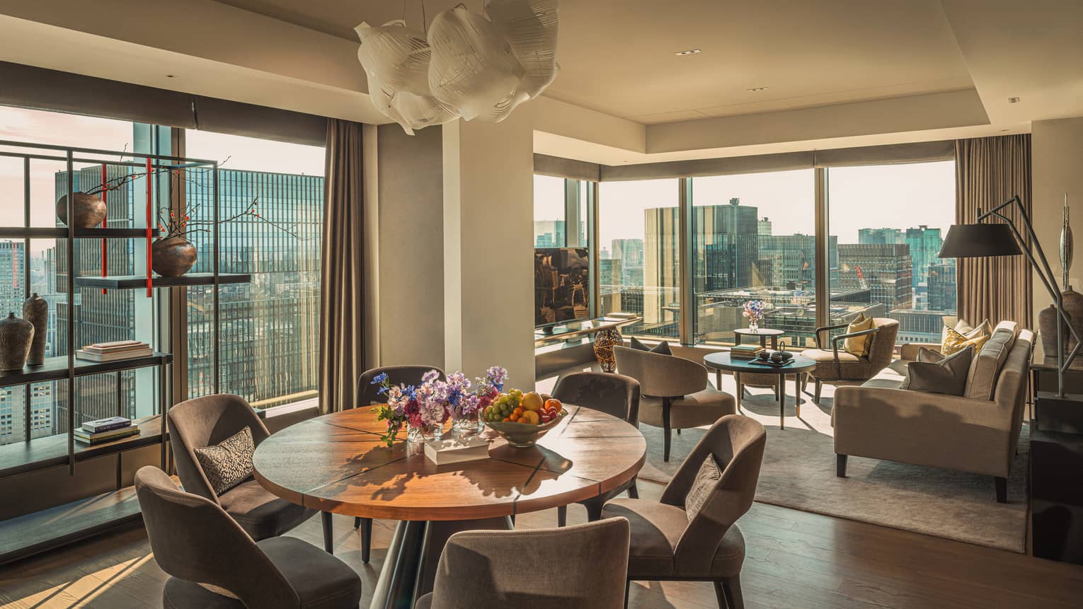 Luxury hotel suite featuring a living room and dining room with two walls of windows looking out to city view