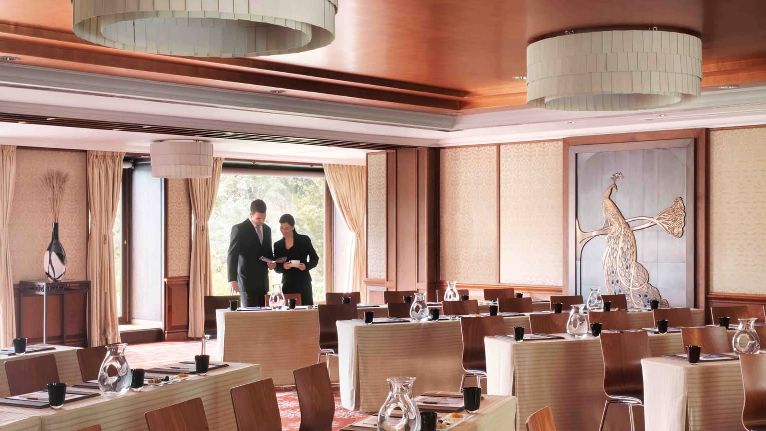 Man and woman in business clothes look at brochure, standing in meeting room