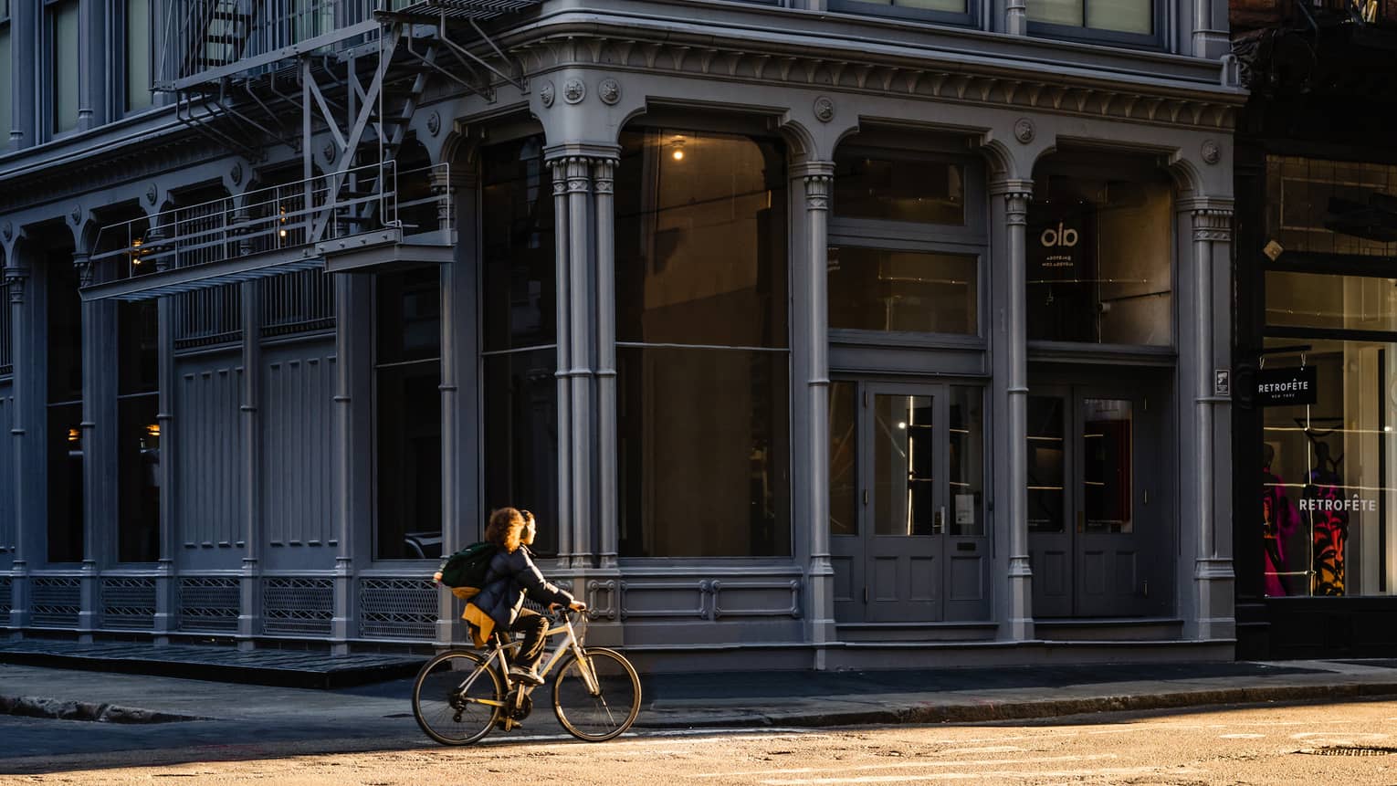 Person rides bike on street past New York City SoHo building