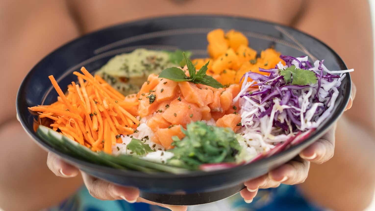 Tahitian woman holding a Salmon Poke Bowl