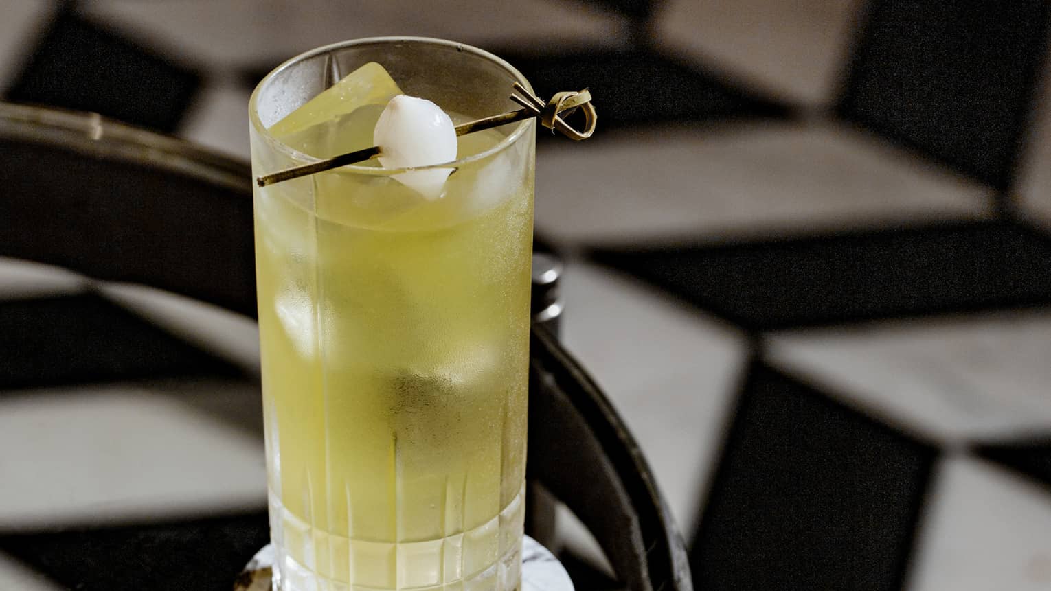 A yellow cocktail on a glass table.
