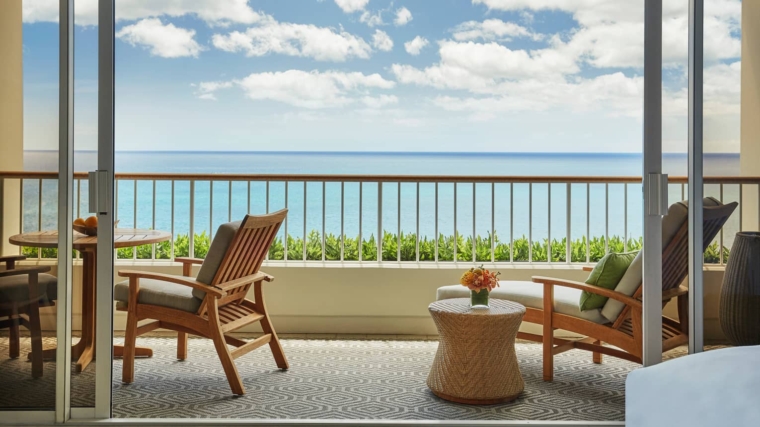 Junior Suite balcony with wood and wicker lounge furniture, ocean views