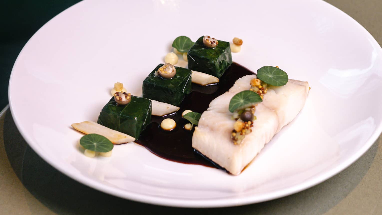  Roasted black cod served on a white plate with spinach subric, celeriac pur�e, salsify and sauce Marchand de Vin