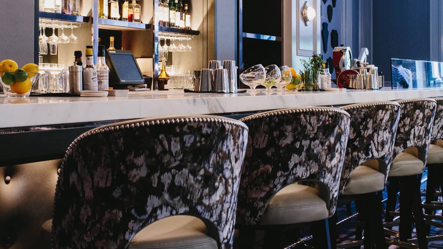 Close-up of velvet backs of bar stools along Bar Margot rail