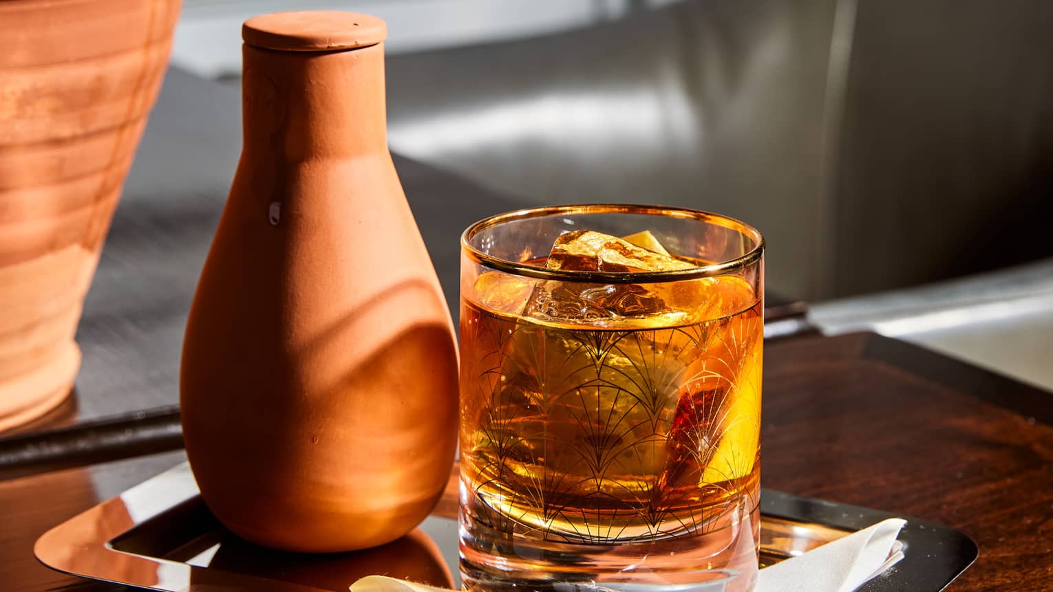 A drinking glass placed on a tray on a table.
