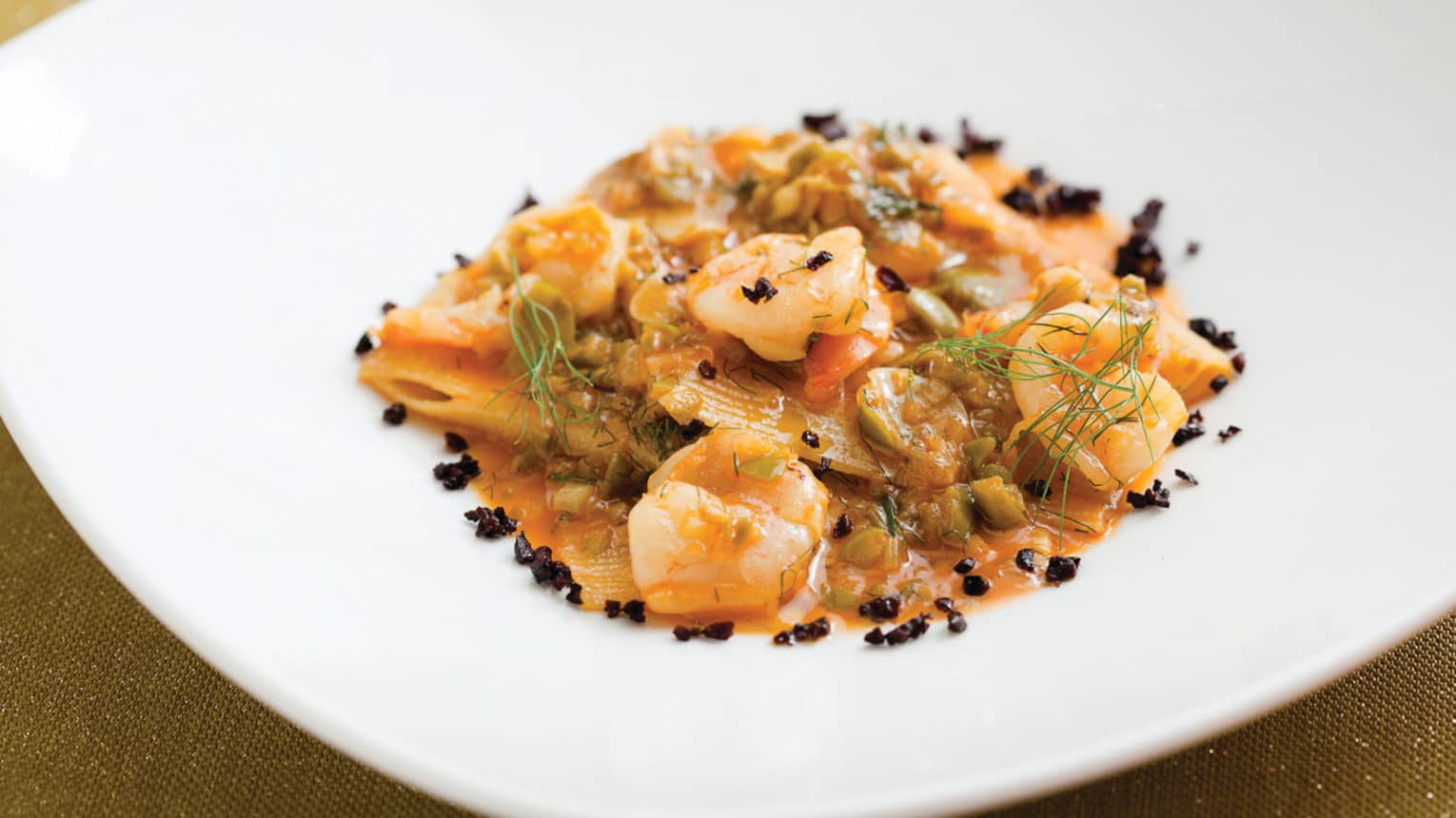 Close-up of seafood, pasta noodles in tomato cream sauce in white dish