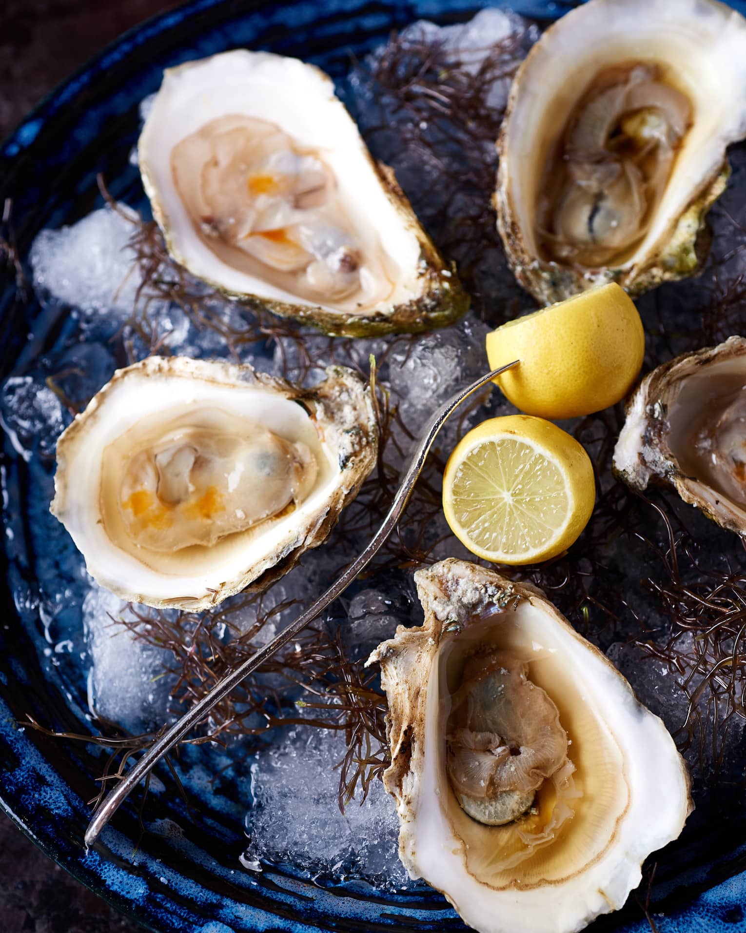 Oysters on a plate with a fork and lemons.