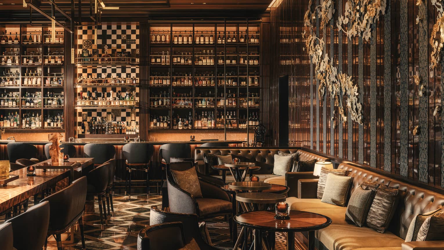 Contemporary bar and lounge, with leather seating and walls lined with beverage bottles