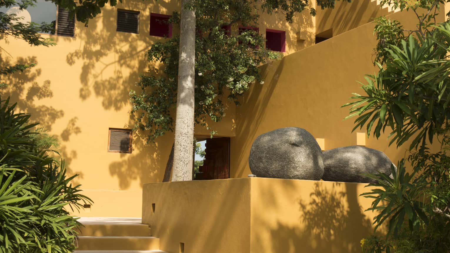 Exterior of yellow stucco villa with trees