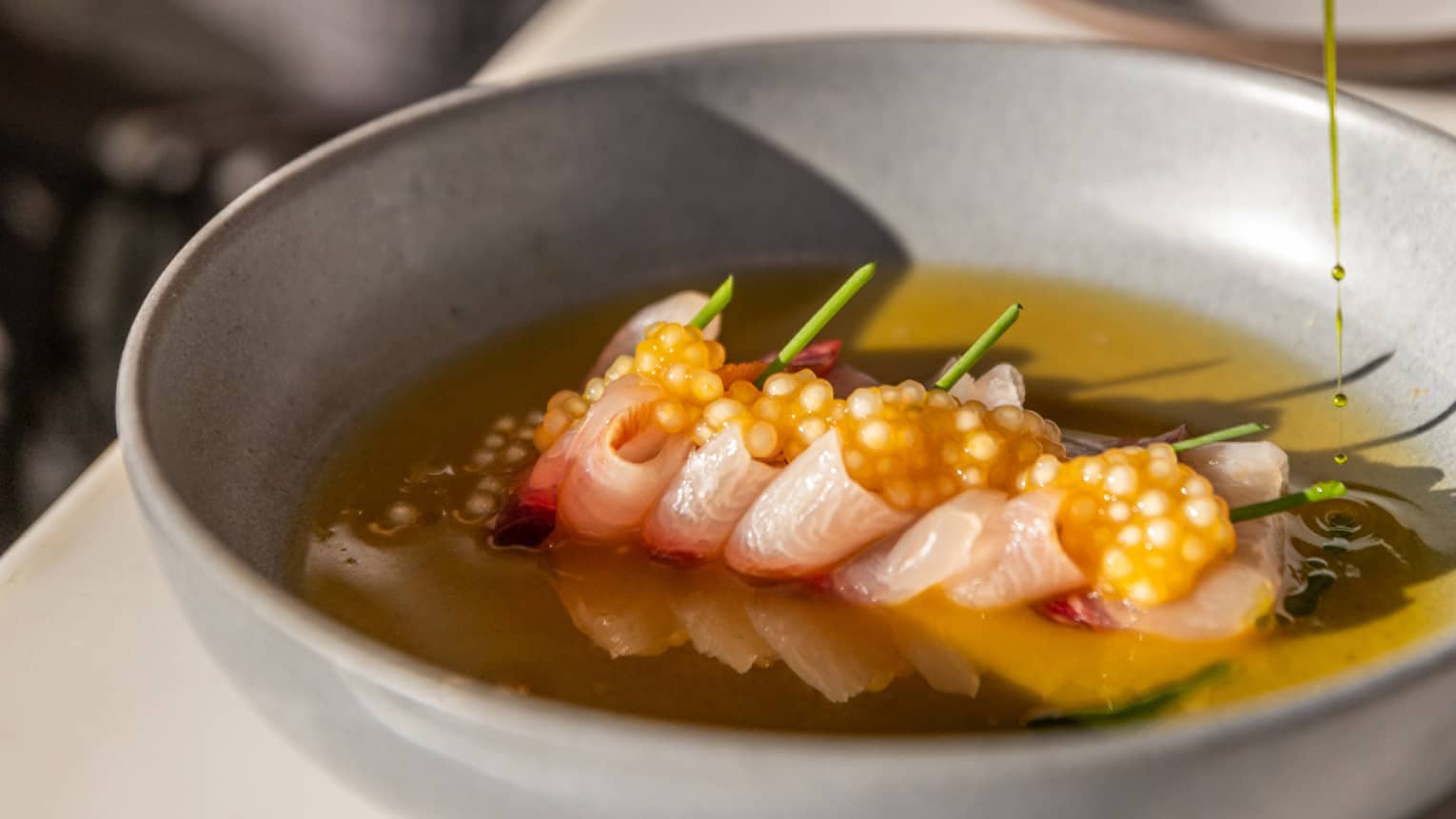 A person eating a bowl of tuna crudo