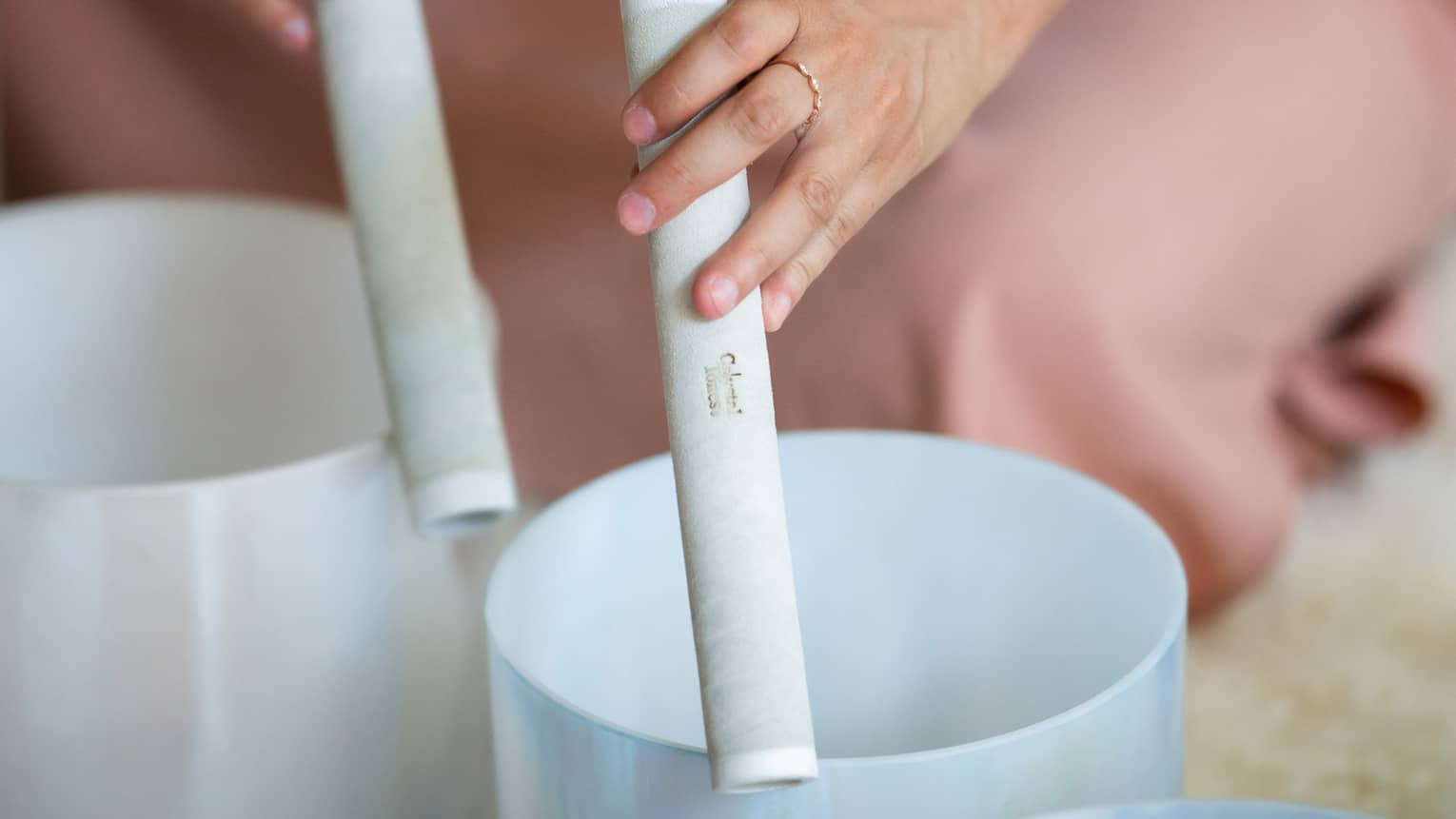 A close up of hands tracing white rollers around empty containers, likely producing a calming, chime noise at a spa session
