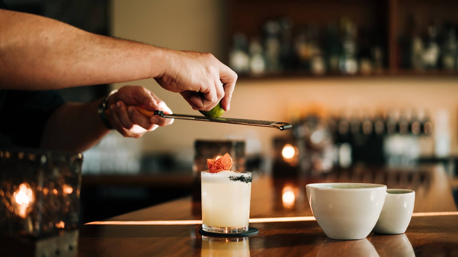 A person standing at a bar and making a drink in a glass