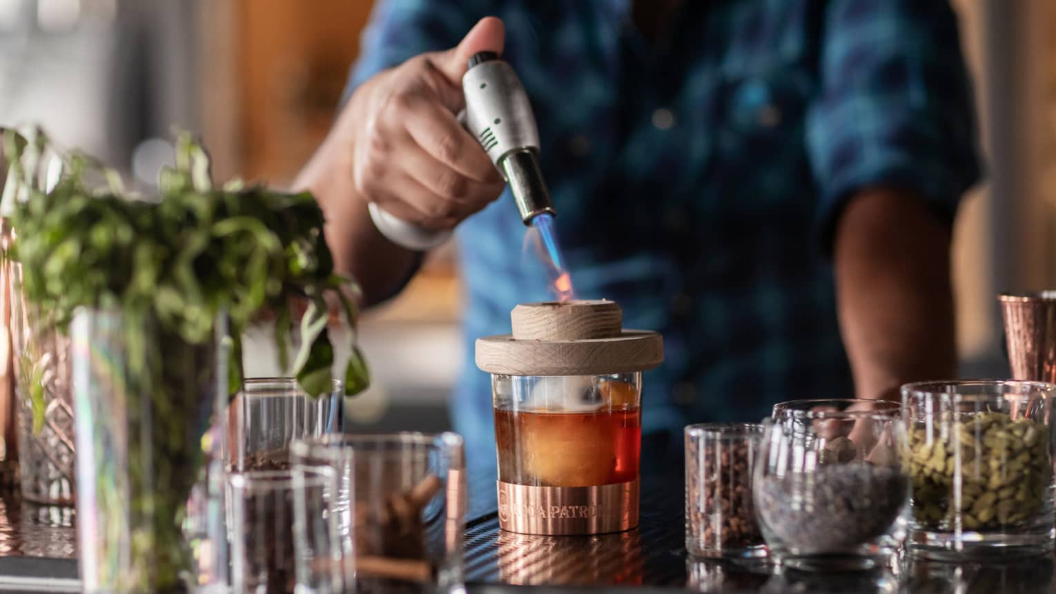 Bartender standing at the bar and using a whiskey torch to make a drink