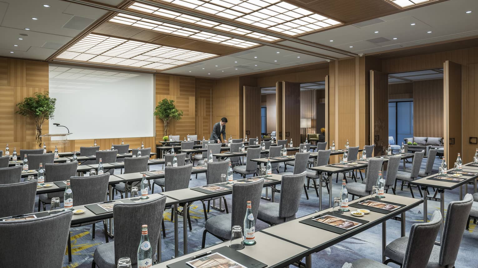 Conference event with rows of meeting tables, chairs facing screen