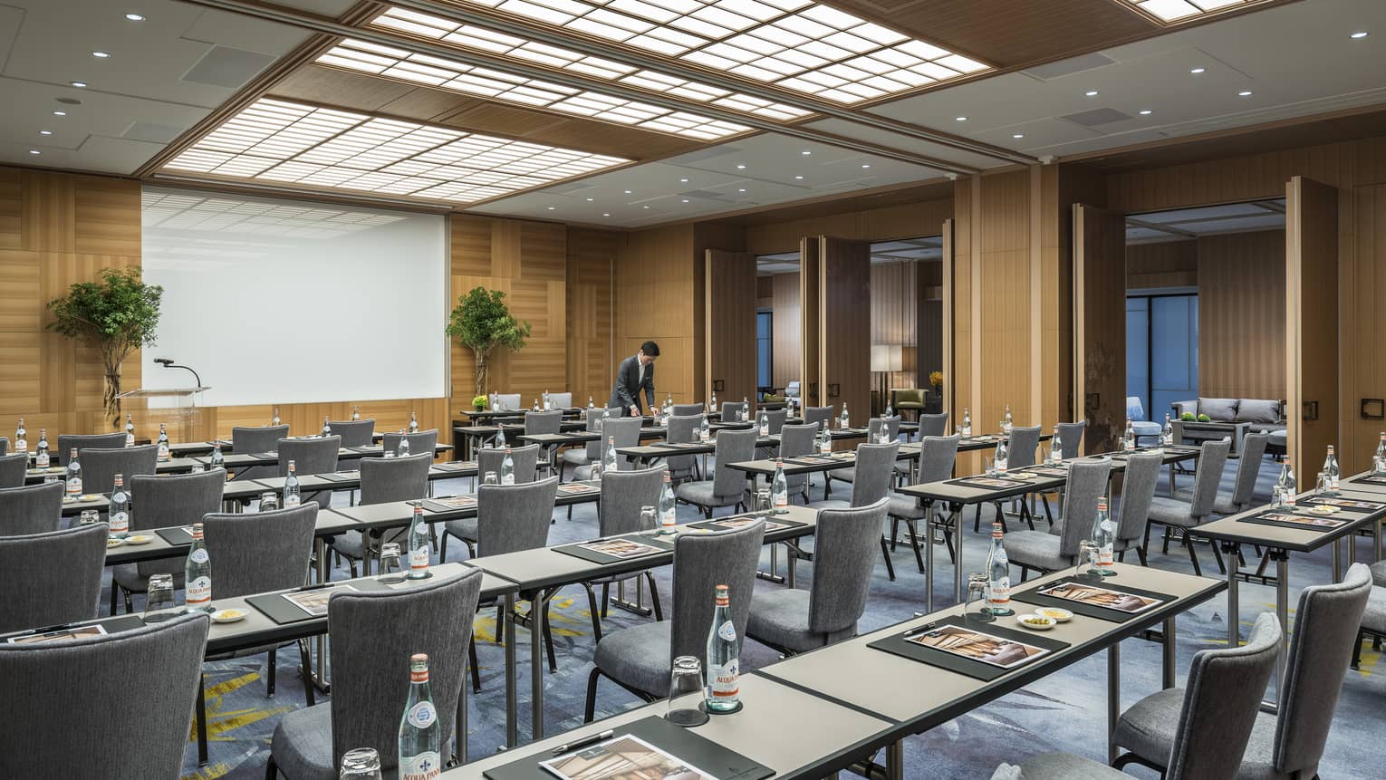 Conference event with rows of meeting tables, chairs facing screen