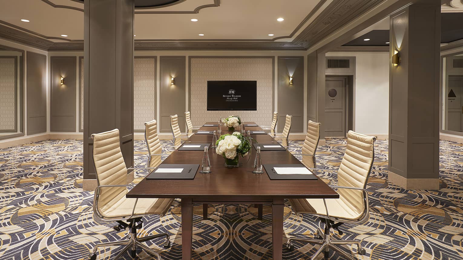 Boardroom setup with gold chairs around brown table in large meeting room.