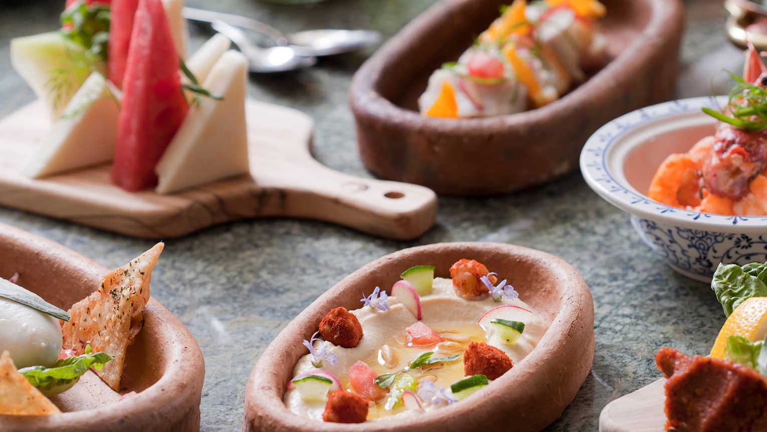Small clay and wood dishes with appetizers, cheeses, fruits