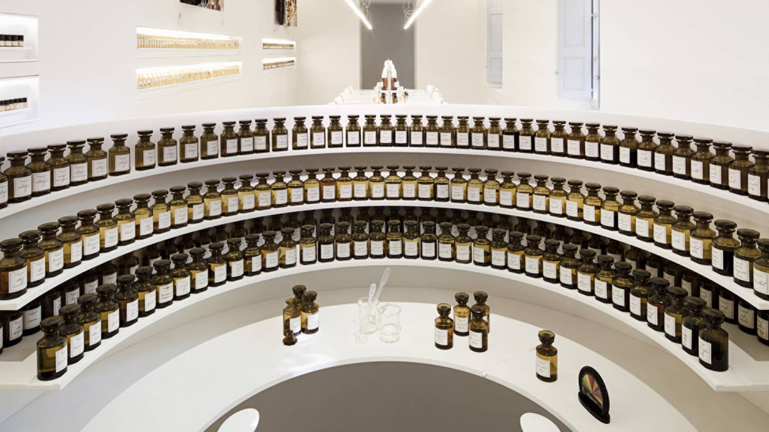 Curved white shelves with small glass tincture bottles at the Fragonard perfume factory