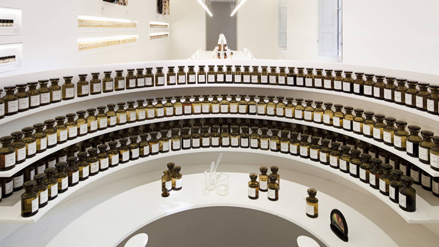 Curved white shelves with small glass tincture bottles at the Fragonard perfume factory