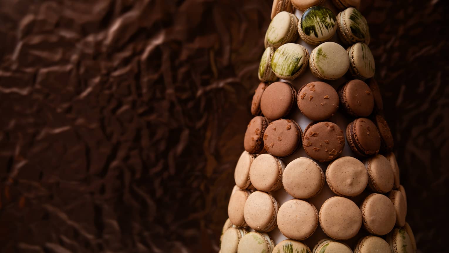 French macrons in shades of brown, beige and light green are artfully displayed in a tree-like shape