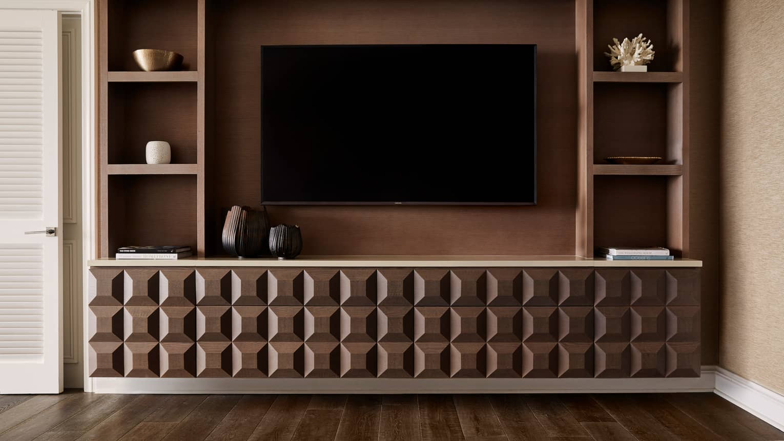 Modern entertainment center with geometric wood design, mounted TV and shelving