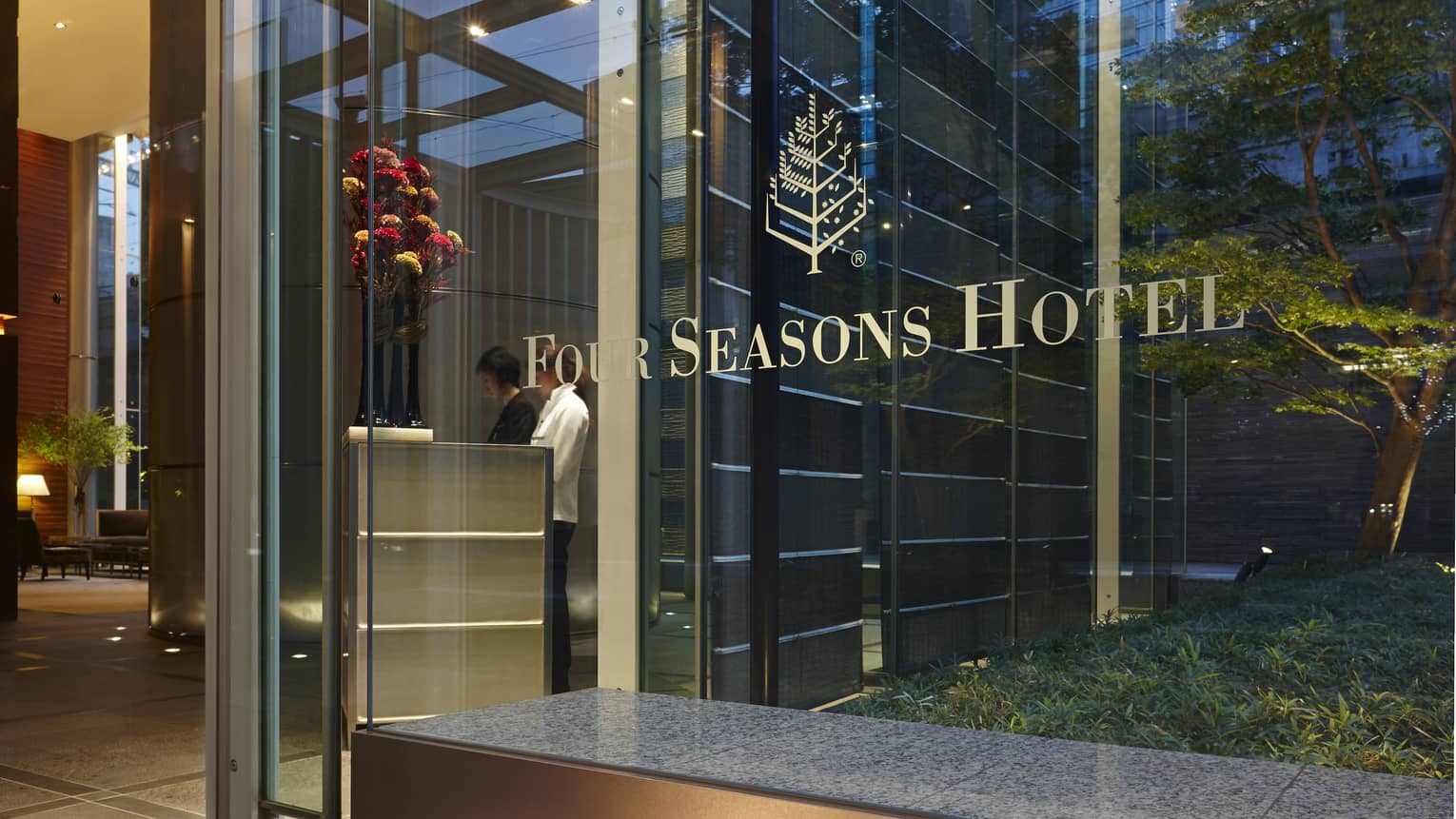 Four Seasons Hotel Tokyo at Marunouchi entrance, logo on glass window with concierges in background