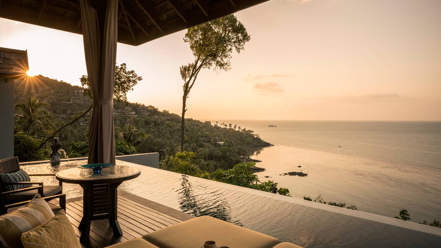 One-bedroom pool villa patio chair, infinity pool overlooking mountain, ocean at sunset