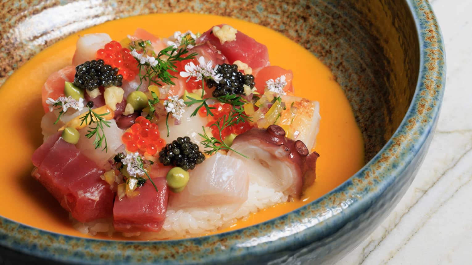 Chirashi ceviche with salmon, tuna, octopus, scallop, ikura, caviar, sushi rice, chalaquita, aji amarillo and leche de tigre served in a stoneware bowl