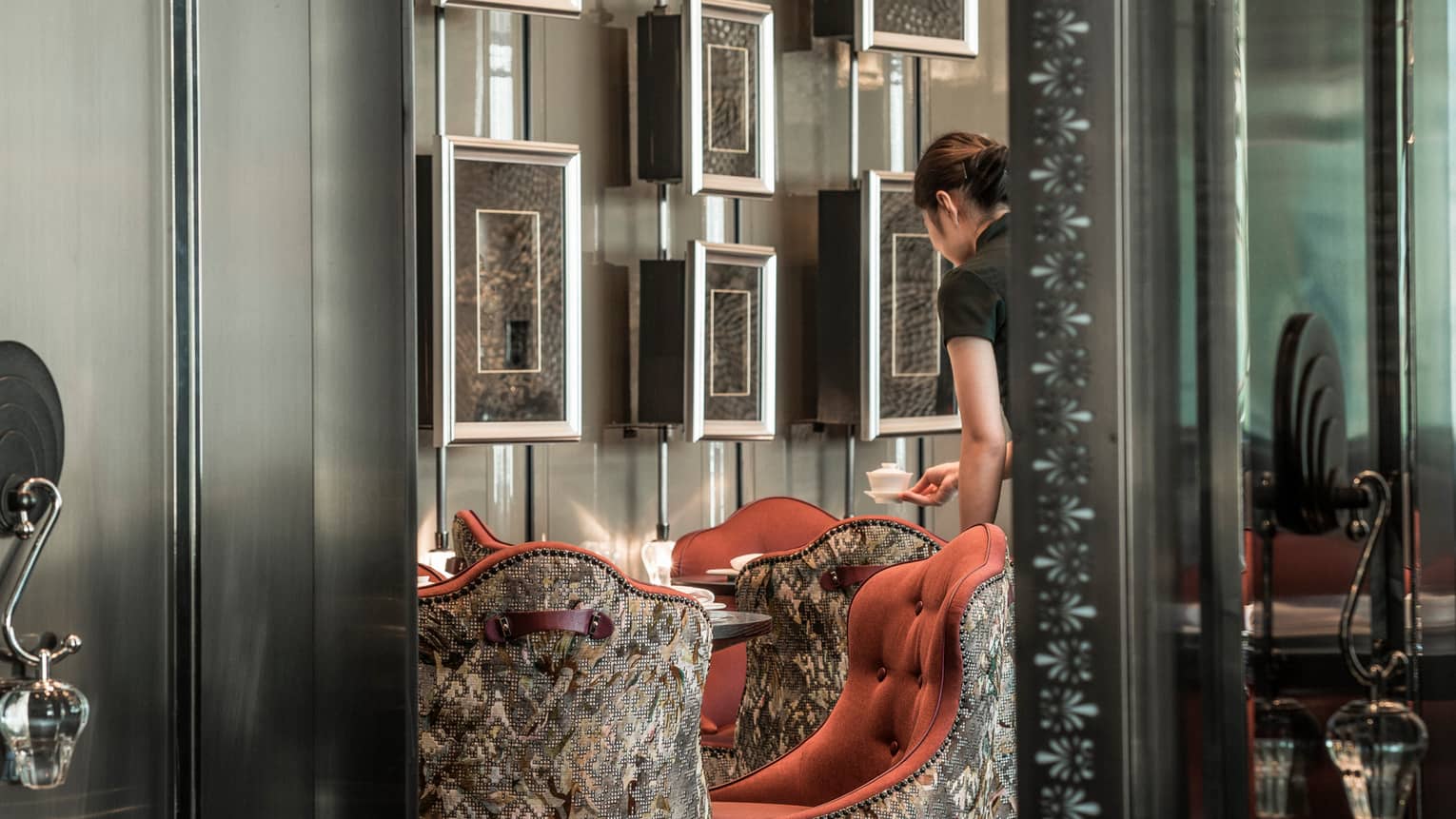Yun House server sets a table with art on the wall in the background