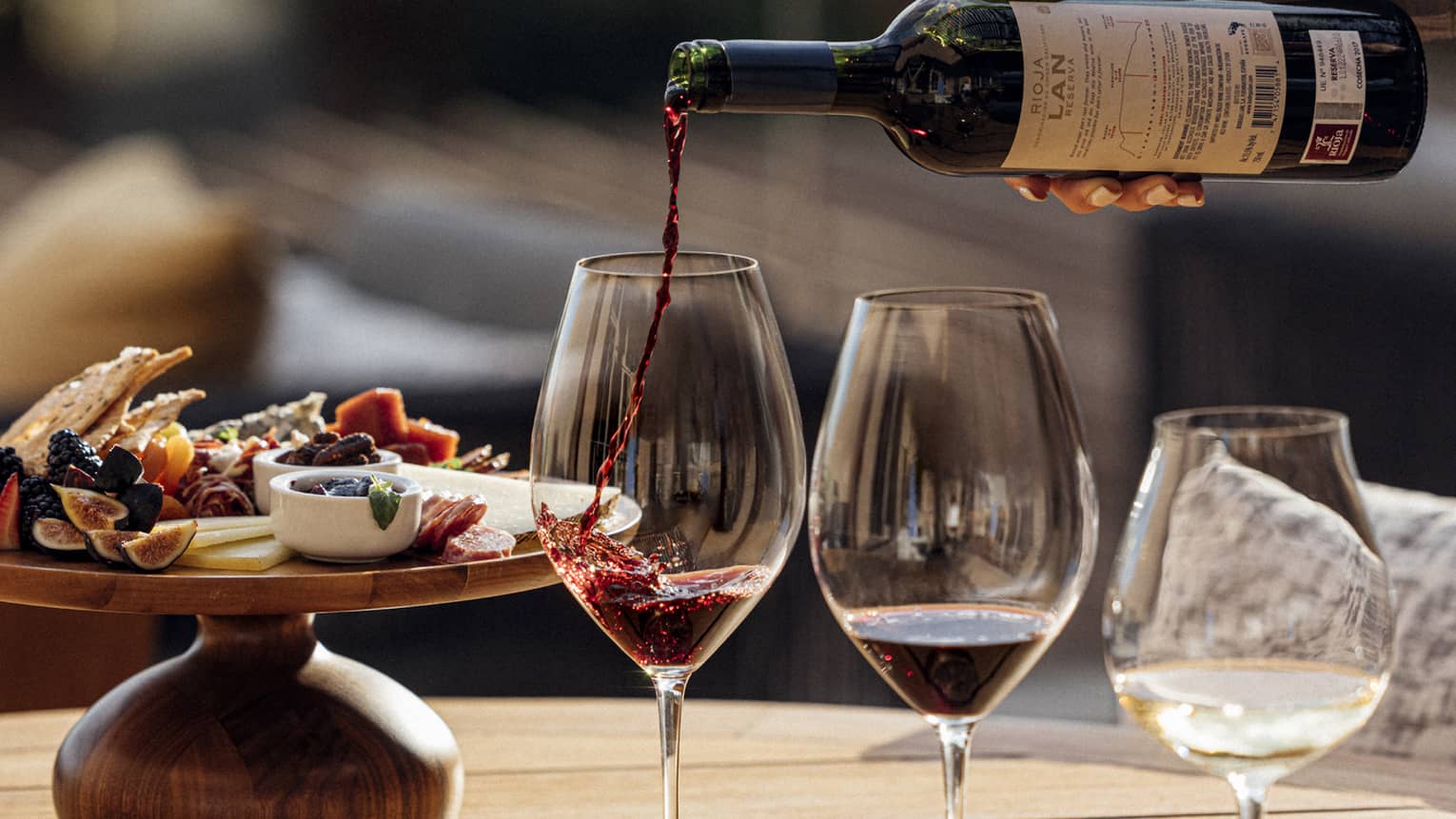 Three glasses of wine are poured next to a plate of charcuterie
