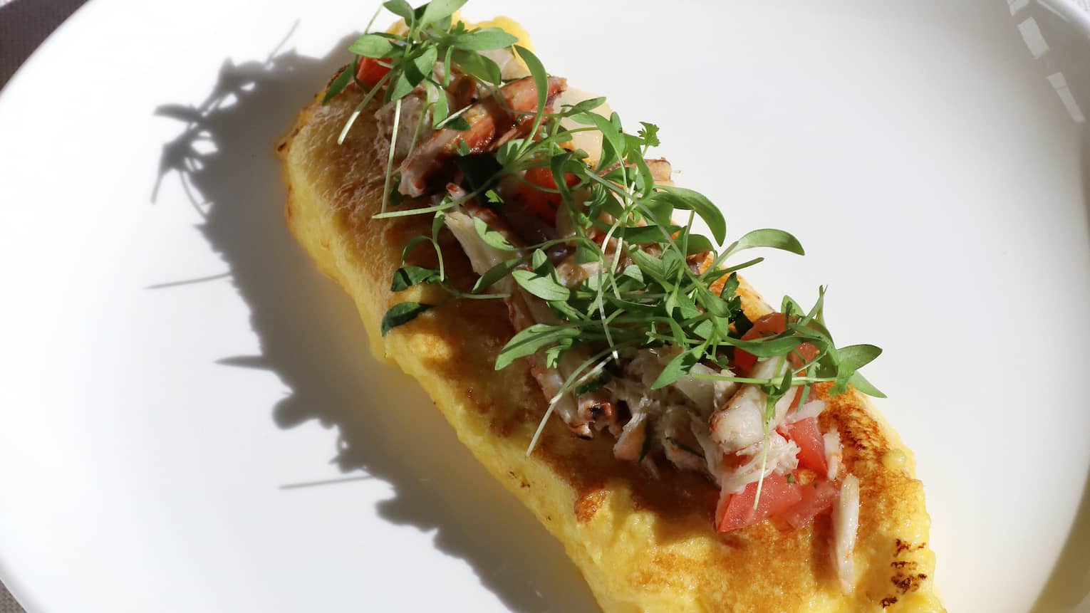 Breakfast omlette and chocolate croissant each served on white plates