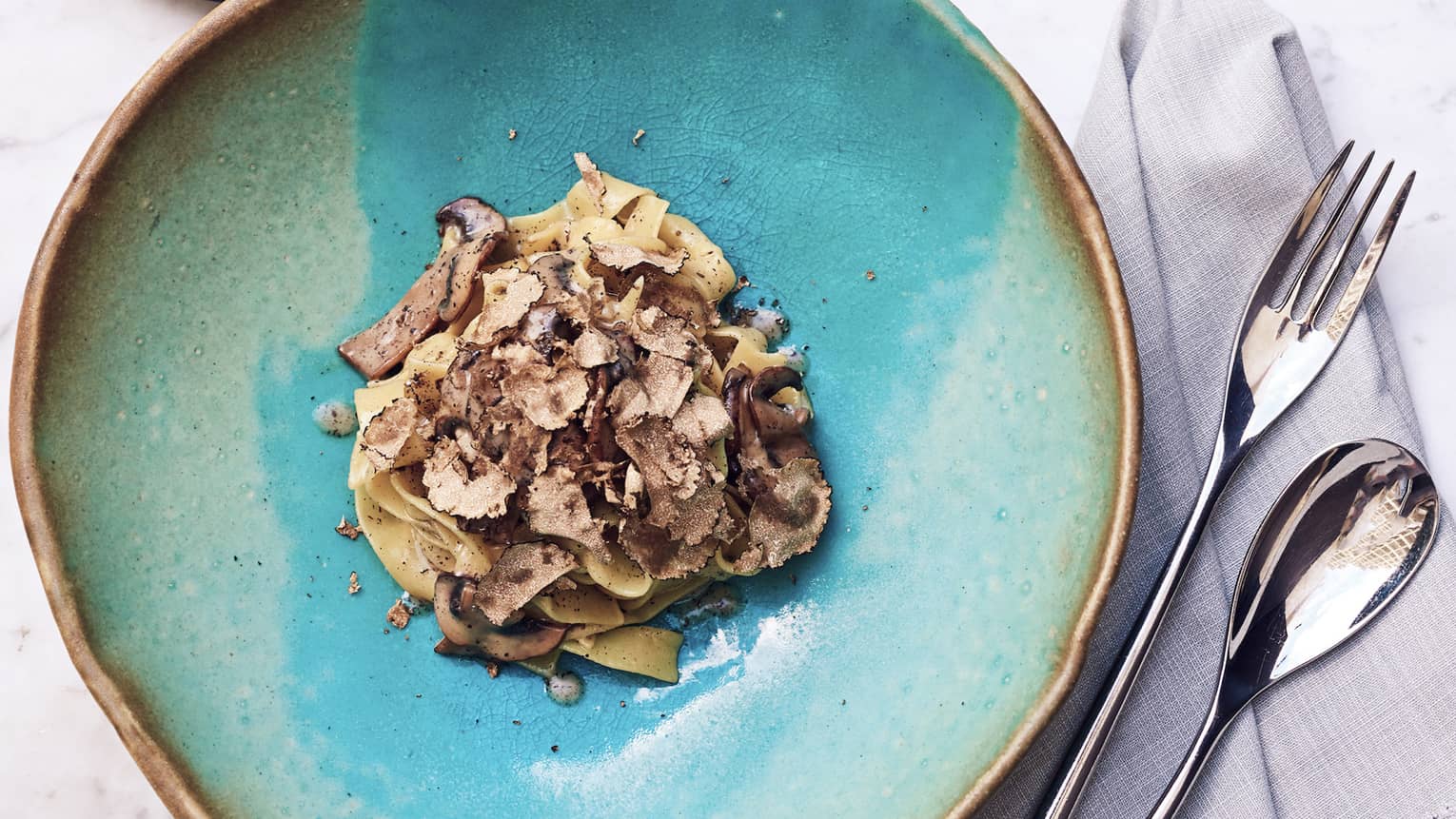 Tagliatelle truffle mushroom pasta on blue plate