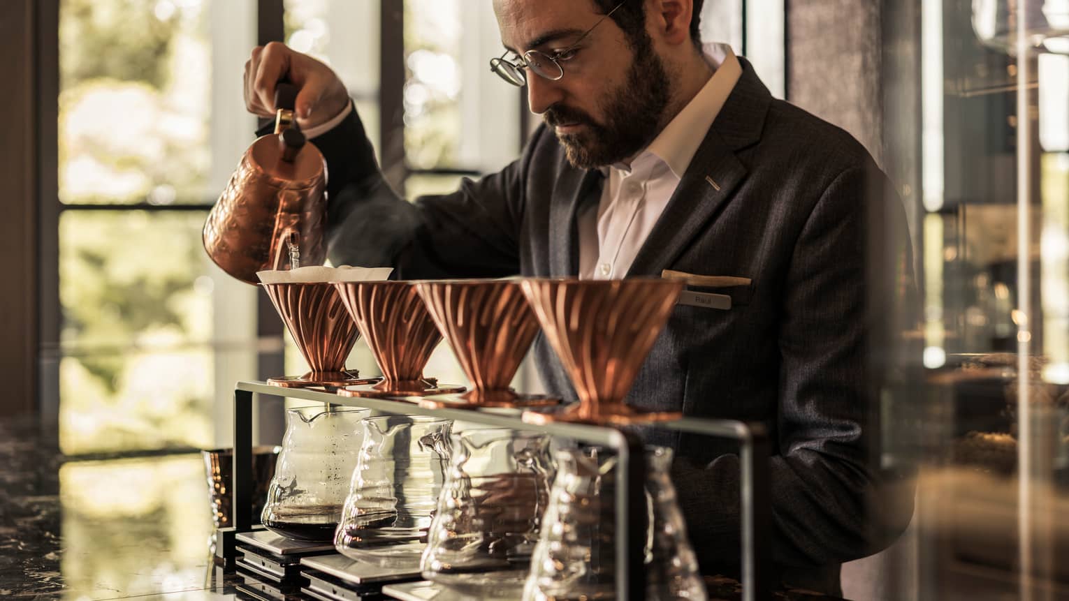 Close-up of server pouring water from copper pot into carafes in The Lounge