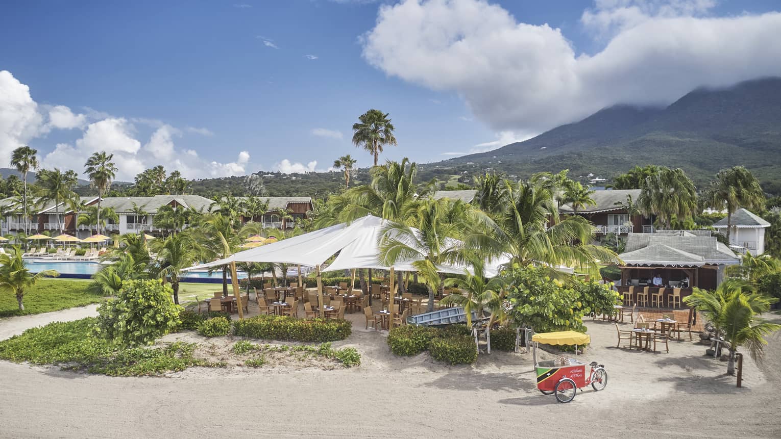 Aerial view of outdoor restaurant with awning, beach, palm trees