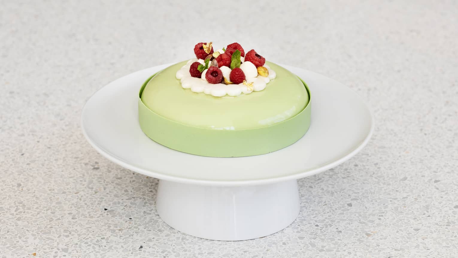 A light green cake with raspberries.