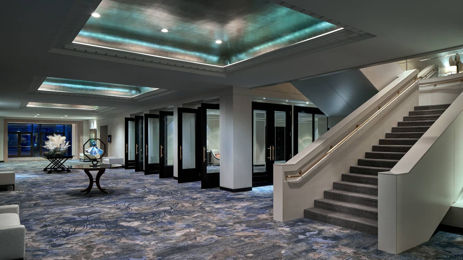 Events hall with blue-ish carpeting, grand staircase and inset metallic ceiling with recessed lights